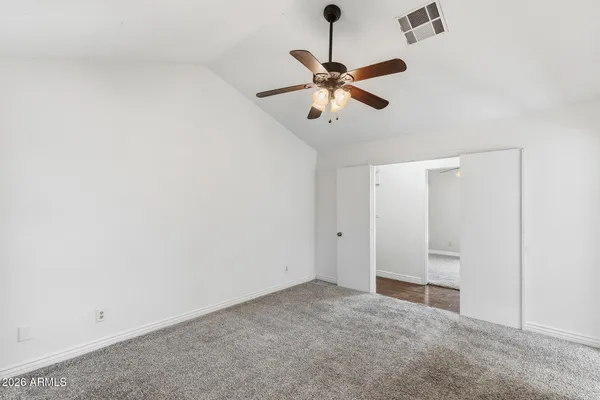 an empty room with closet and a chandelier fan