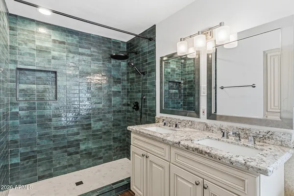 a bathroom with a granite countertop sink a mirror and shower