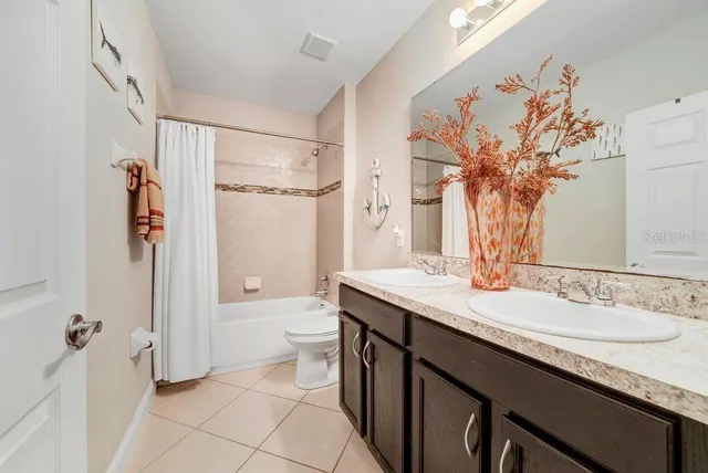a bathroom with a granite countertop sink a toilet a mirror and shower