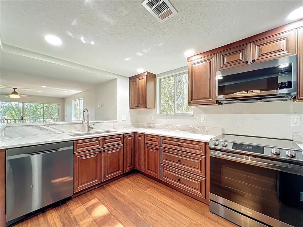 9736 Indian Key Trail, Unit 111 Seminole, FL 33776 - Photo 11 of 56 a kitchen with stainless steel appliances granite countertop a stove microwave and cabinets