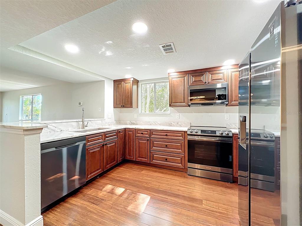 9736 Indian Key Trail, Unit 111 Seminole, FL 33776 - Photo 10 of 56 a large kitchen with stainless steel appliances granite countertop a stove and a sink
