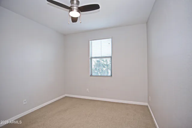 an empty room with a ceiling fan and window