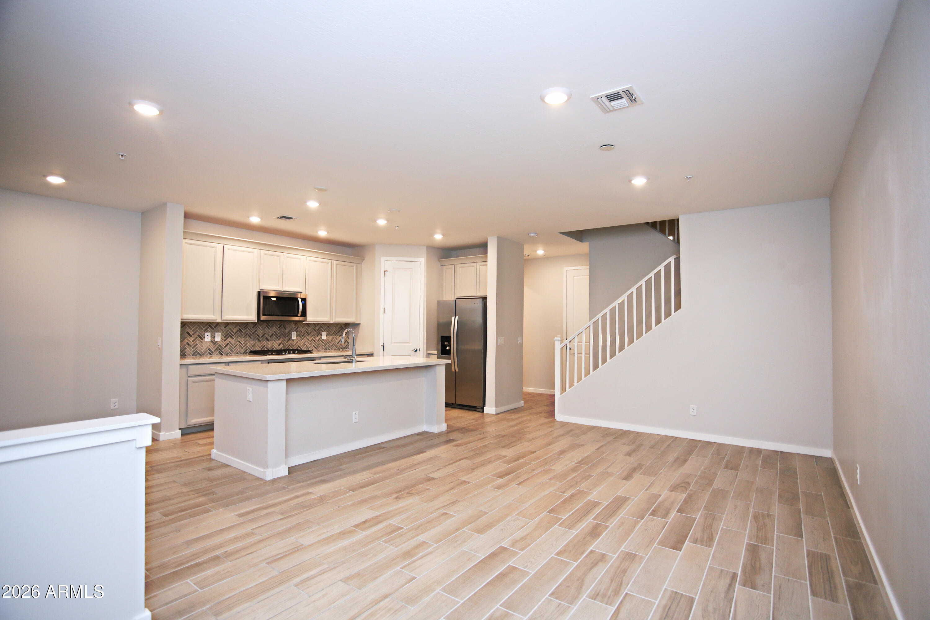 3855 South McQueen Road, Unit 110 Chandler, AZ 85286 - Photo 6 of 37 a kitchen with stainless steel appliances kitchen island wooden floors and white walls