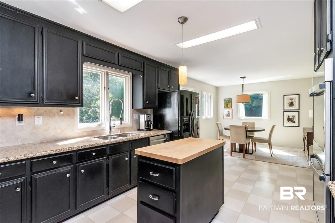305 Fern Hill Court Mobile, AL 36608 - Photo 15 of 53 Kitchen with sink, tasteful backsplash, decorative light fixtures, black refrigerator with ice dispenser, and a center island