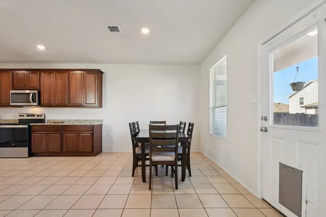a kitchen with stainless steel appliances granite countertop a stove a sink a dining table and chairs