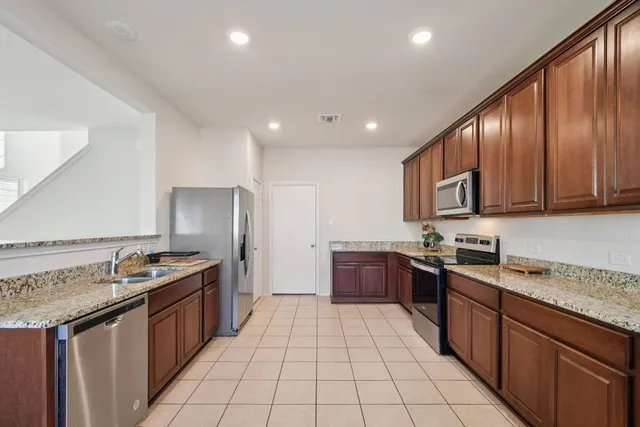 a kitchen with stainless steel appliances granite countertop stove top oven a sink dishwasher and a refrigerator