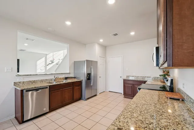 a kitchen with stainless steel appliances granite countertop a stove a sink and a refrigerator