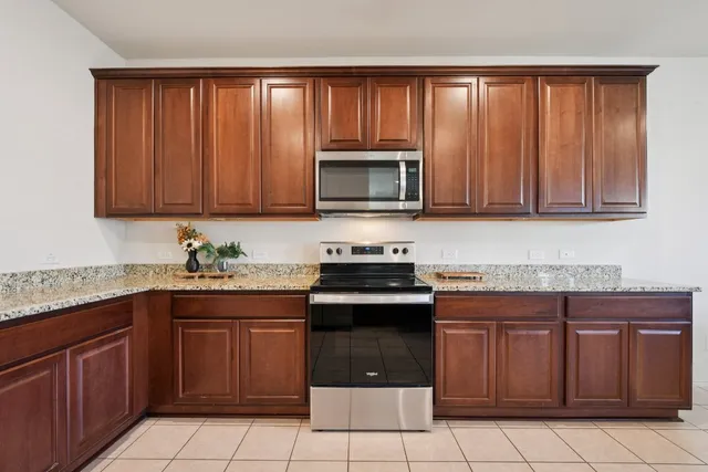 a kitchen with granite countertop a stove top oven microwave and cabinets
