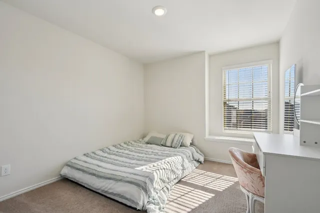 a bedroom with a bed and a window with chair
