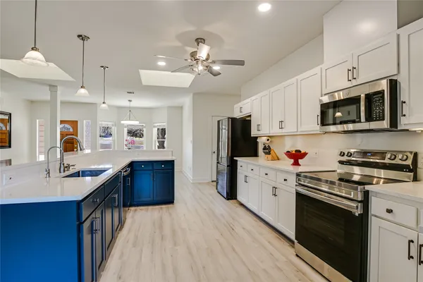 a kitchen with stainless steel appliances kitchen island granite countertop a refrigerator a stove top oven a sink dishwasher and wooden cabinets
