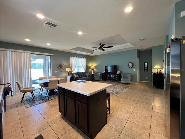 a large dining hall with stainless steel appliances kitchen island granite countertop a large counter top a couches and kitchen view