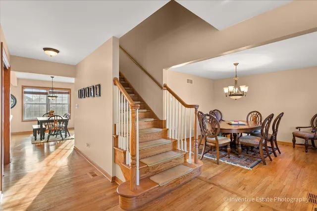 a dining room with wooden floor a chandelier a glass table and chairs