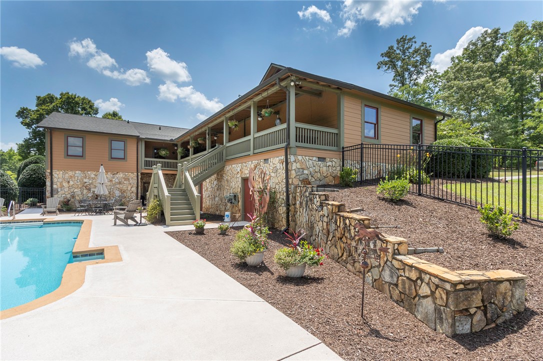 911 State Rd S-4-203 Belton, SC 29627 - Photo 42 of 49 A spacious home with stone accents and a pool, offering a covered porch for outdoor relaxation.