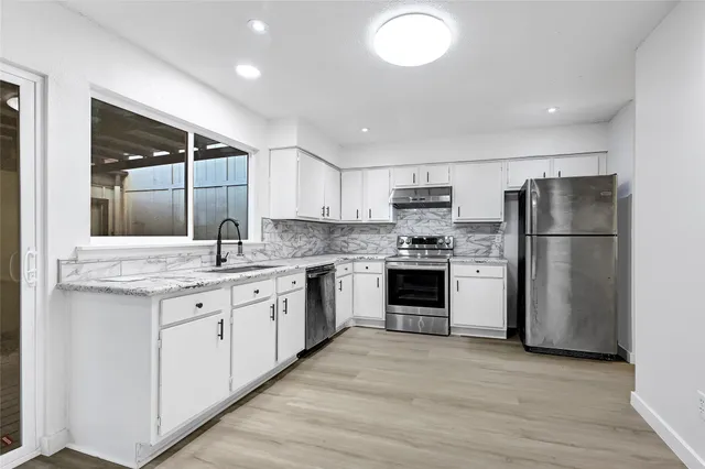 a kitchen with a sink a refrigerator and a stove top oven