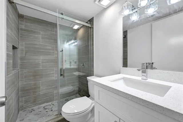 a bathroom with a sink a toilet a mirror and shower