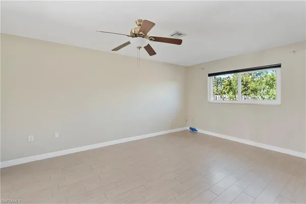 an empty room with windows and fan