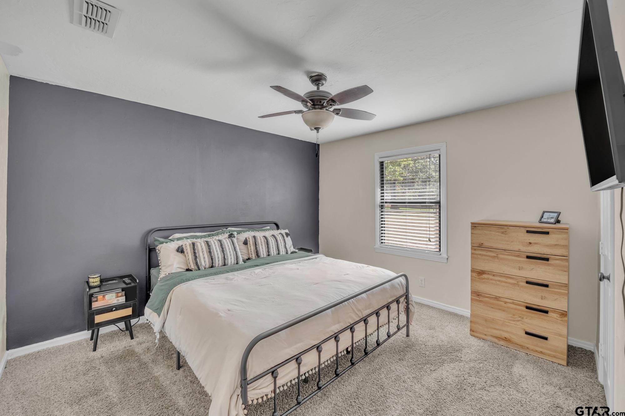 3601 Dumas Road Longview, TX 75604 - Photo 18 of 27 a bedroom with a bed a dresser and a chandelier