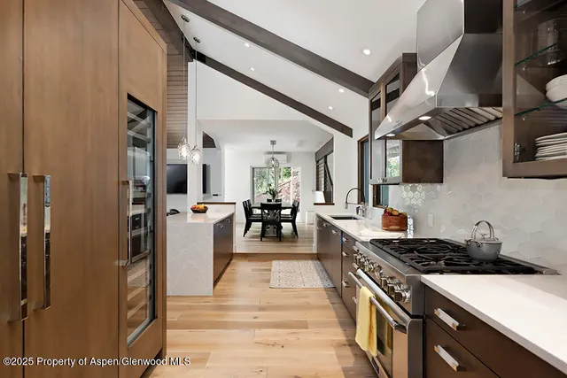 a kitchen with stainless steel appliances granite countertop a refrigerator a stove and a wooden floors