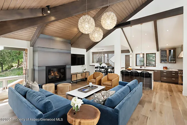 a living room with furniture a fireplace and large windows