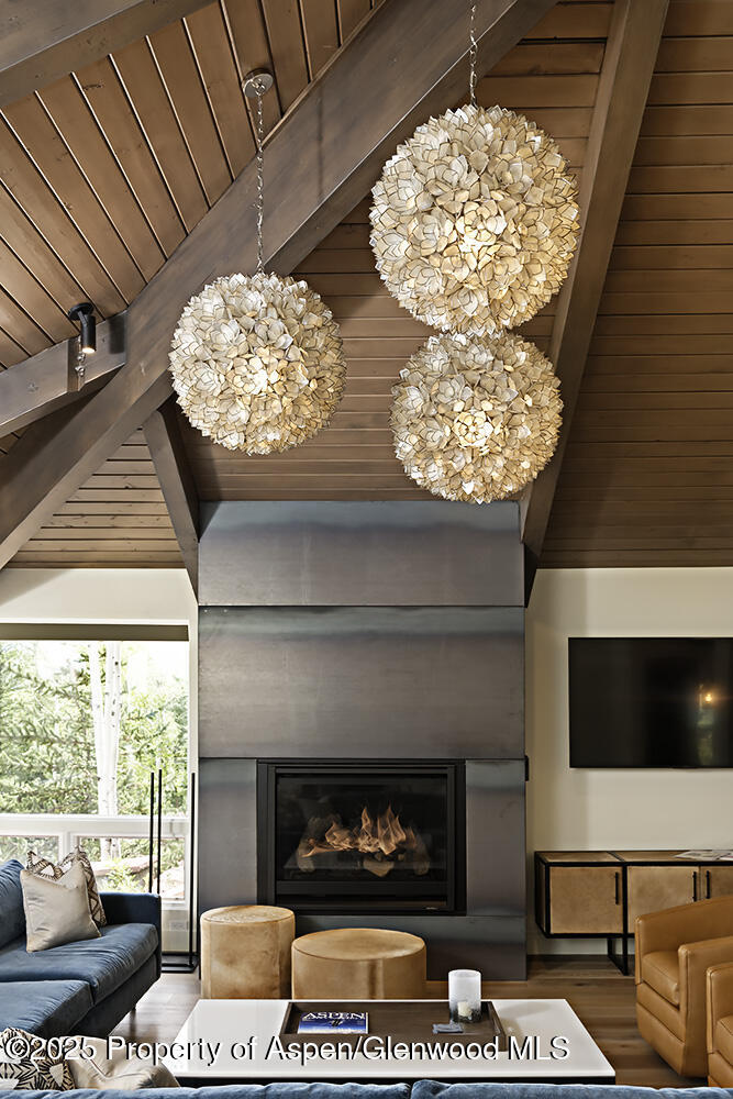 333 Faraway Road Snowmass Village, CO 81615 - Photo 8 of 29 a living room with a fireplace a flat screen tv and a large window