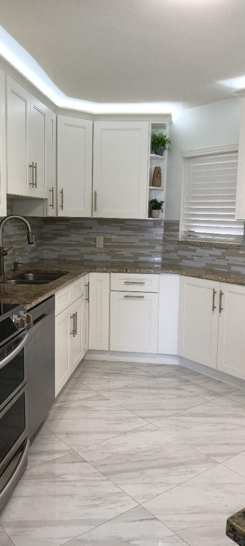 5749 Camino Del Sol, Unit 202 Boca Raton, FL 33433 - Photo 12 of 39 a kitchen with granite countertop a sink and a stove