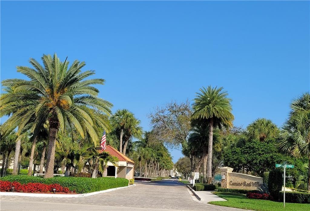 5749 Camino Del Sol, Unit 202 Boca Raton, FL 33433 - Photo 2 of 39 a front view of a house with a yard and palm trees