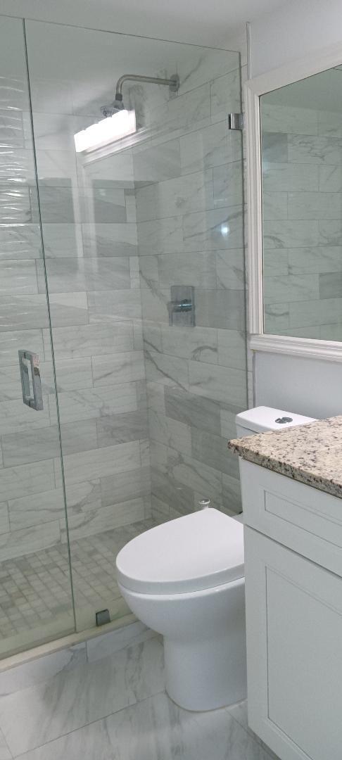 5749 Camino Del Sol, Unit 202 Boca Raton, FL 33433 - Photo 23 of 39 a bathroom with a granite countertop toilet a sink and shower