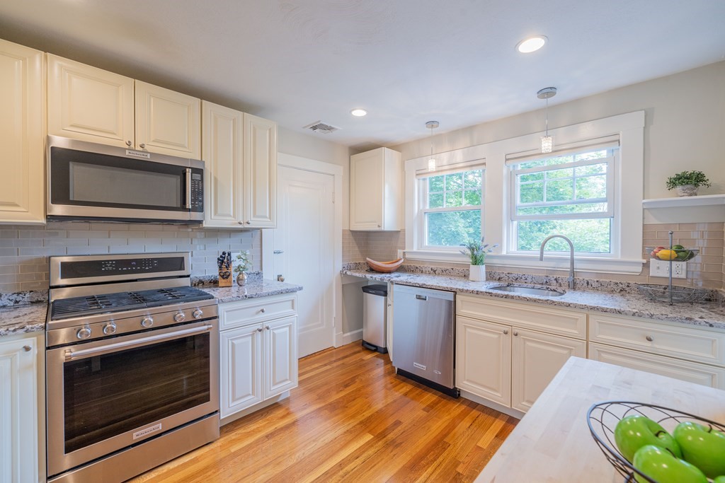 7 Maynard Street, Unit 2 Arlington, MA 02474 - Photo 20 of 42 a kitchen with stainless steel appliances a stove a sink cabinets and a wooden floor