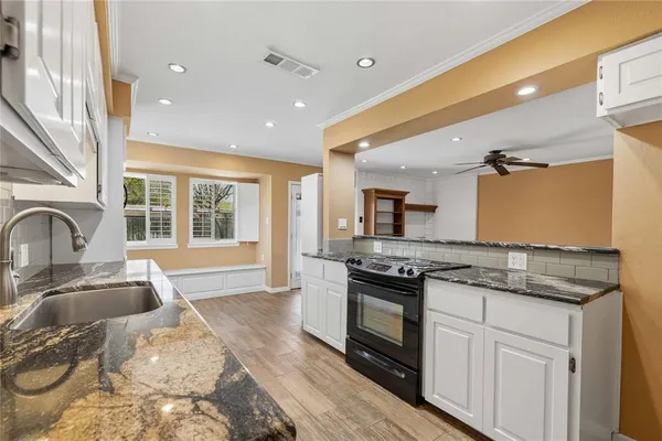 a kitchen with granite countertop a sink stove and cabinets