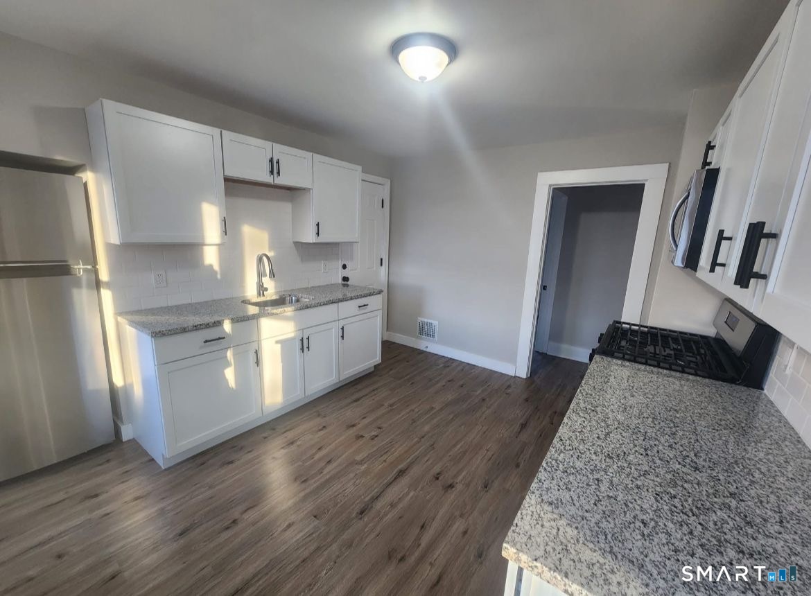 282 Ward Street Wallingford, CT 06492 - Photo 3 of 6 a kitchen with stainless steel appliances granite countertop a refrigerator a stove and a wooden floors