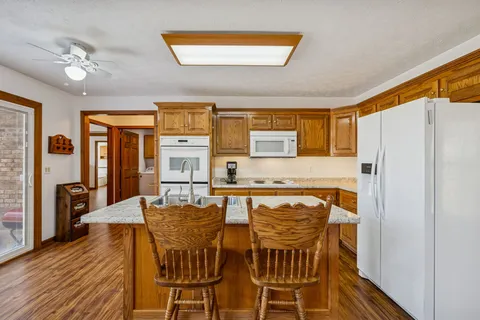 a kitchen with stainless steel appliances granite countertop a stove a refrigerator a dining table and chairs with wooden floor