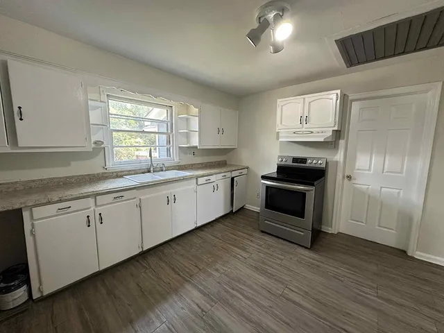 a kitchen with granite countertop white cabinets and wooden floor