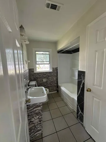 a spacious bathroom with a granite countertop sink a toilet and bathtub