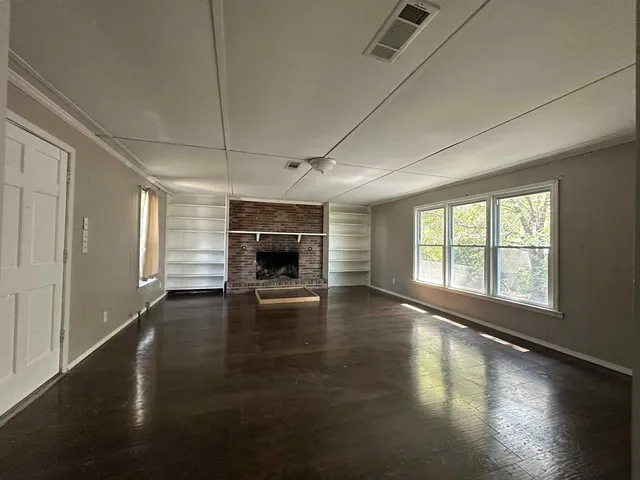 an empty room with floor to ceiling windows and fireplace