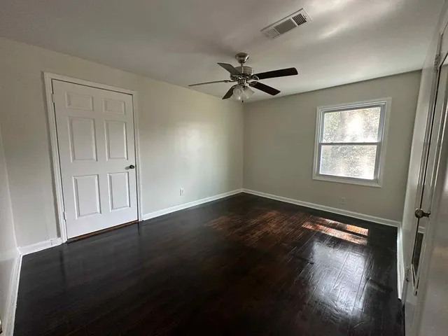 a view of empty room with wooden floor and fan
