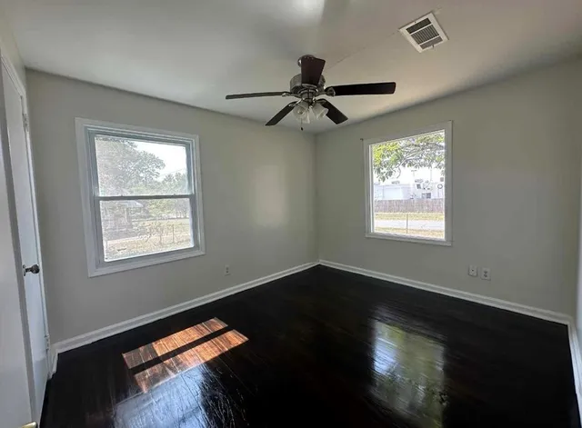 a view of an empty room with wooden floor and a window