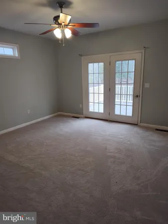 en empty room with windows and chandelier fan