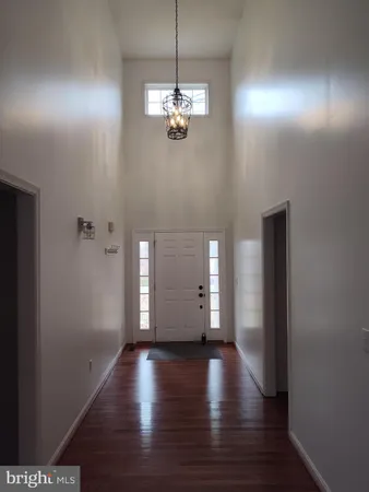 a view of a hallway with wooden floor and a chandelier