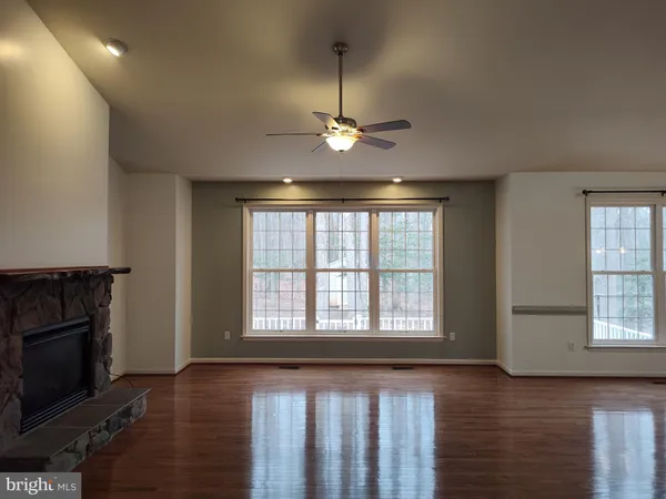 a view of an empty room with wooden floor fireplace and a window