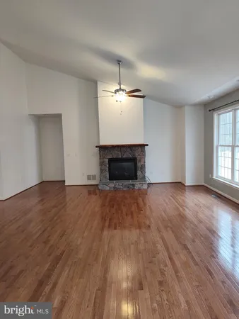 an empty room with wooden floor fireplace and windows