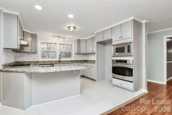 a kitchen with granite countertop stainless steel appliances sink stove and cabinets