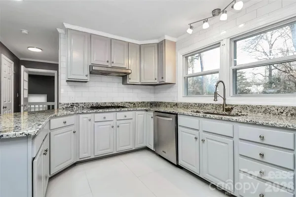 an empty room with wooden floor fireplace and windows
