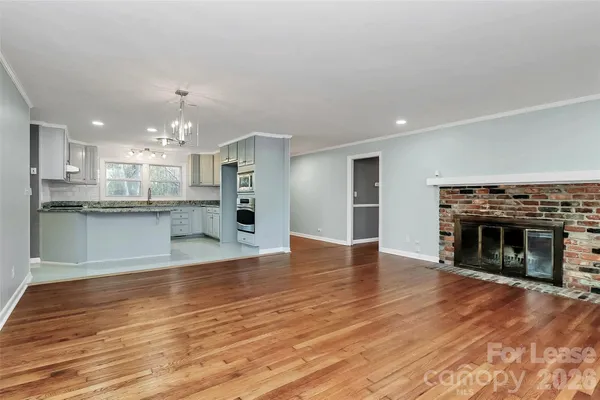 an empty room with wooden floor a ceiling fan and windows