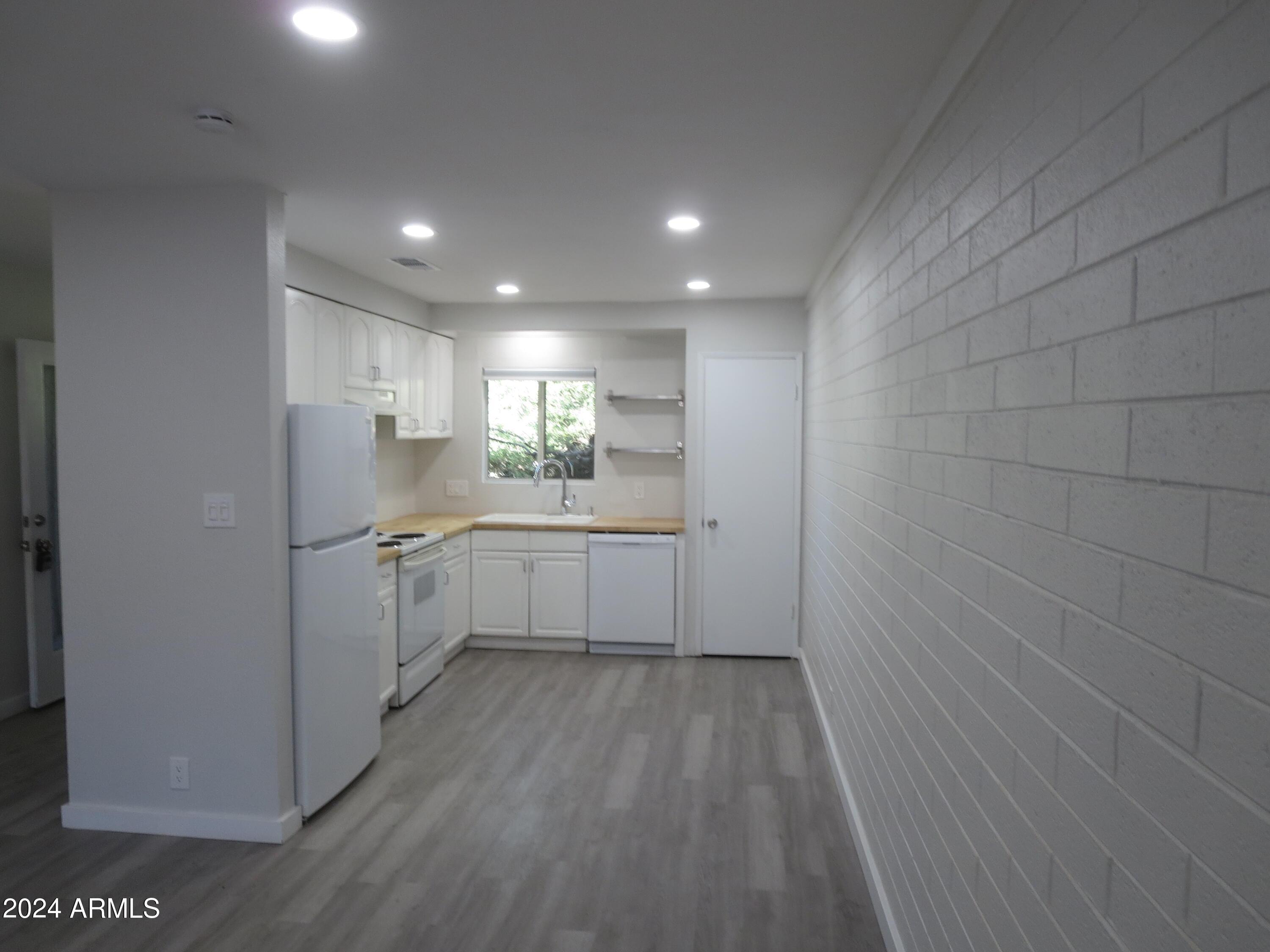1450 East Bethany Home Road, Unit 34 Phoenix, AZ 85014 - Photo 4 of 15 a kitchen with white cabinets and white appliances