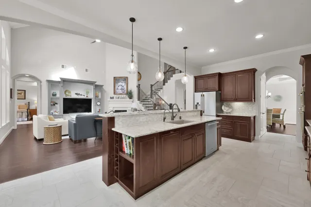 a large kitchen with a large counter top a sink stainless steel appliances and cabinets