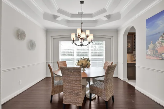 a dining room with furniture a chandelier and wooden floor
