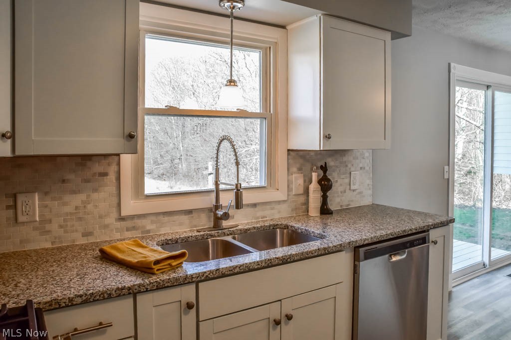 The kitchen has stainless steel appliances and wooded views from the sink.