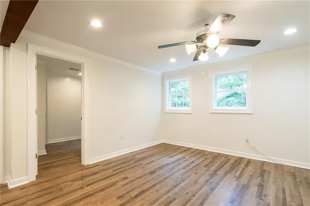 an empty room with wooden floor chandelier fan and windows