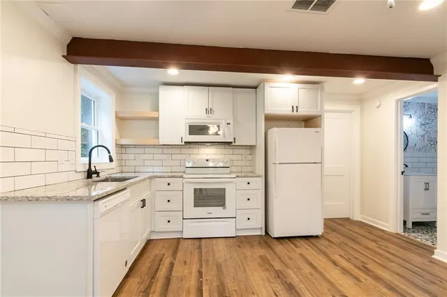 a kitchen with a sink a refrigerator and white cabinets