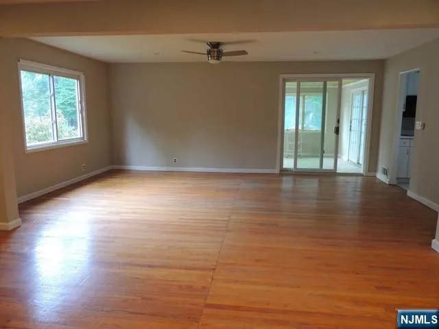 a view of an empty room with wooden floor and a window